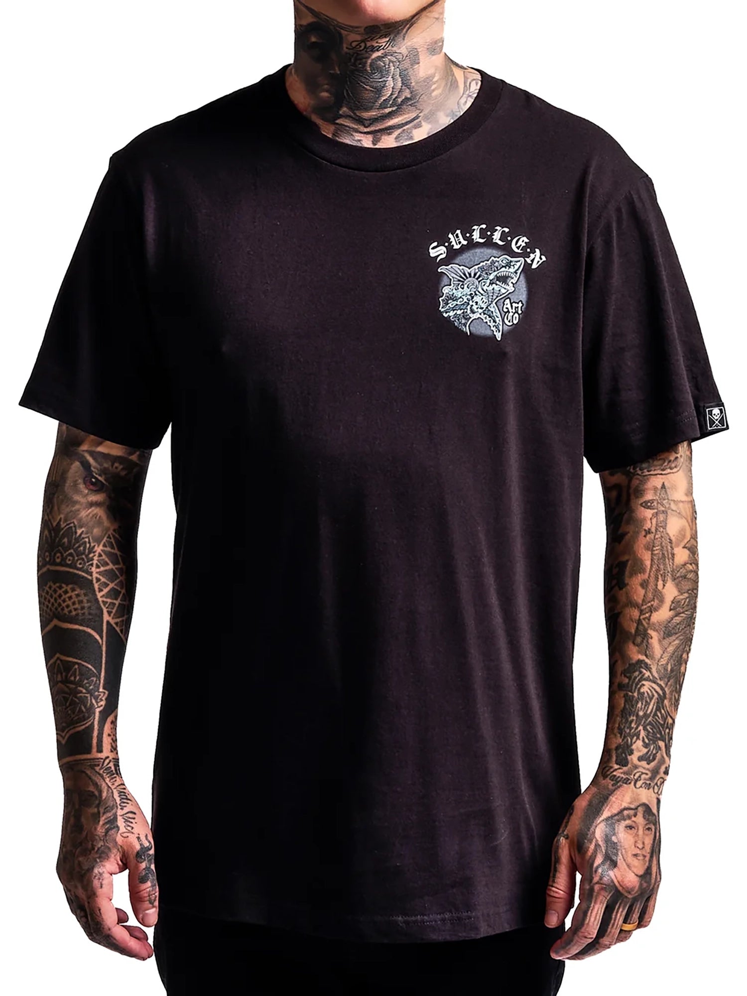 A man wearing a black short-sleeve t-shirt with a white and gray graphic on the left chest. The graphic features the word 'SURREY' in a gothic font above a detailed skull illustration.