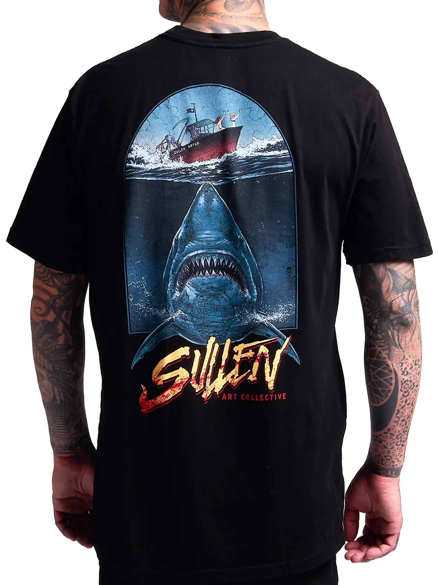 A man wearing a black t-shirt, viewed from the back, featuring a large graphic print of a shark and a fishing boat with the text 'SULLEN ART COLLECTIVE'.