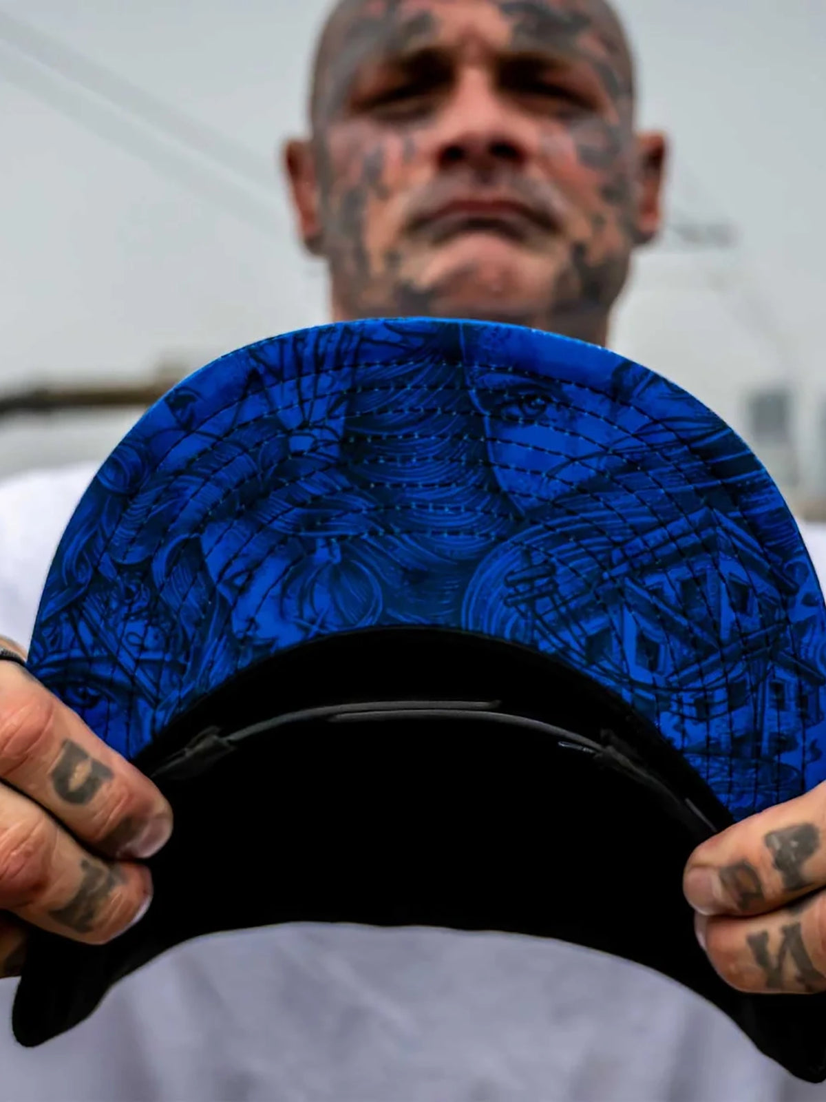 Model holding the Sullen Sad Boy snapback to display its blue illustrated underbill